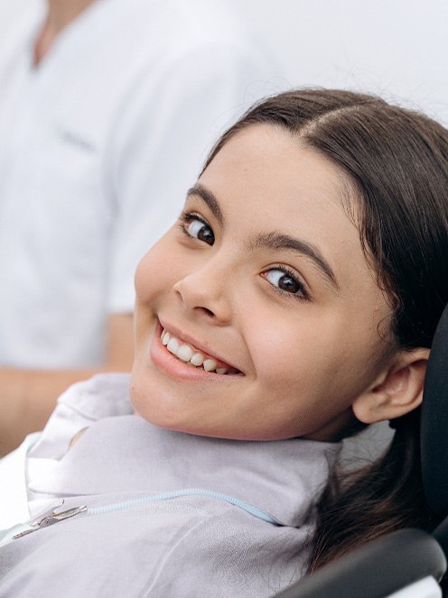 Child smiling while sitting in treatment chair