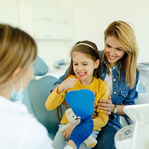 Child sitting on mom's lap while brushing teeth
