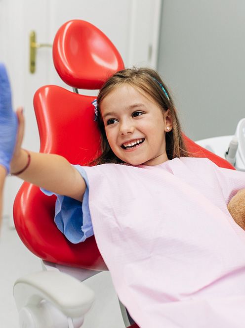 Child smiling while giving dentist high five