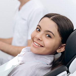 Child smiling while sitting in treatment chair