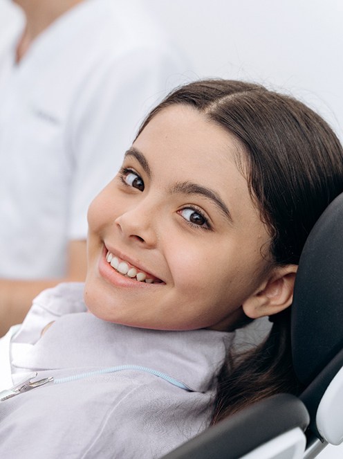 Child smiling while sitting in treatment chair