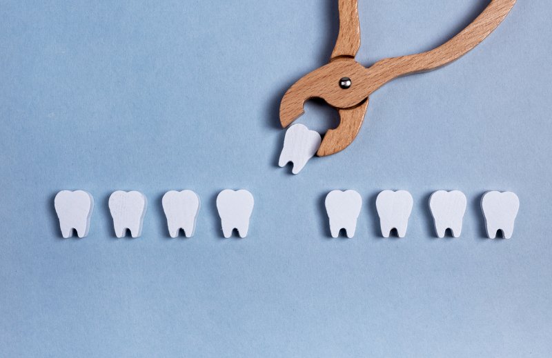 Toy model of wooden dental tool performing a baby tooth extraction