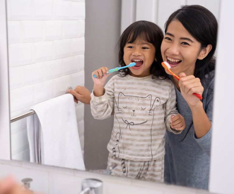 Mom showing toddler how to brush teeth